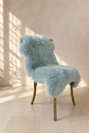 Duck Egg sheepskin draped over a wooden chair in a warm neutral interior