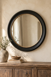 Round black-and-gold mirror hung on the wall in a Society House-style interior